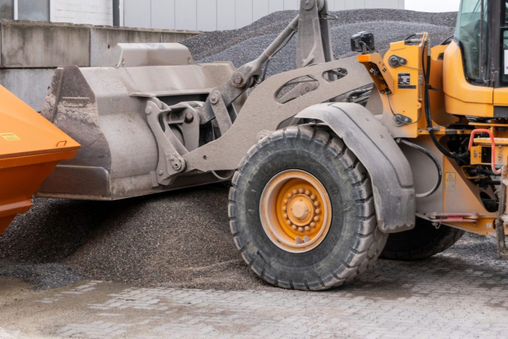 Yellow loader scooping gravel into orange truck